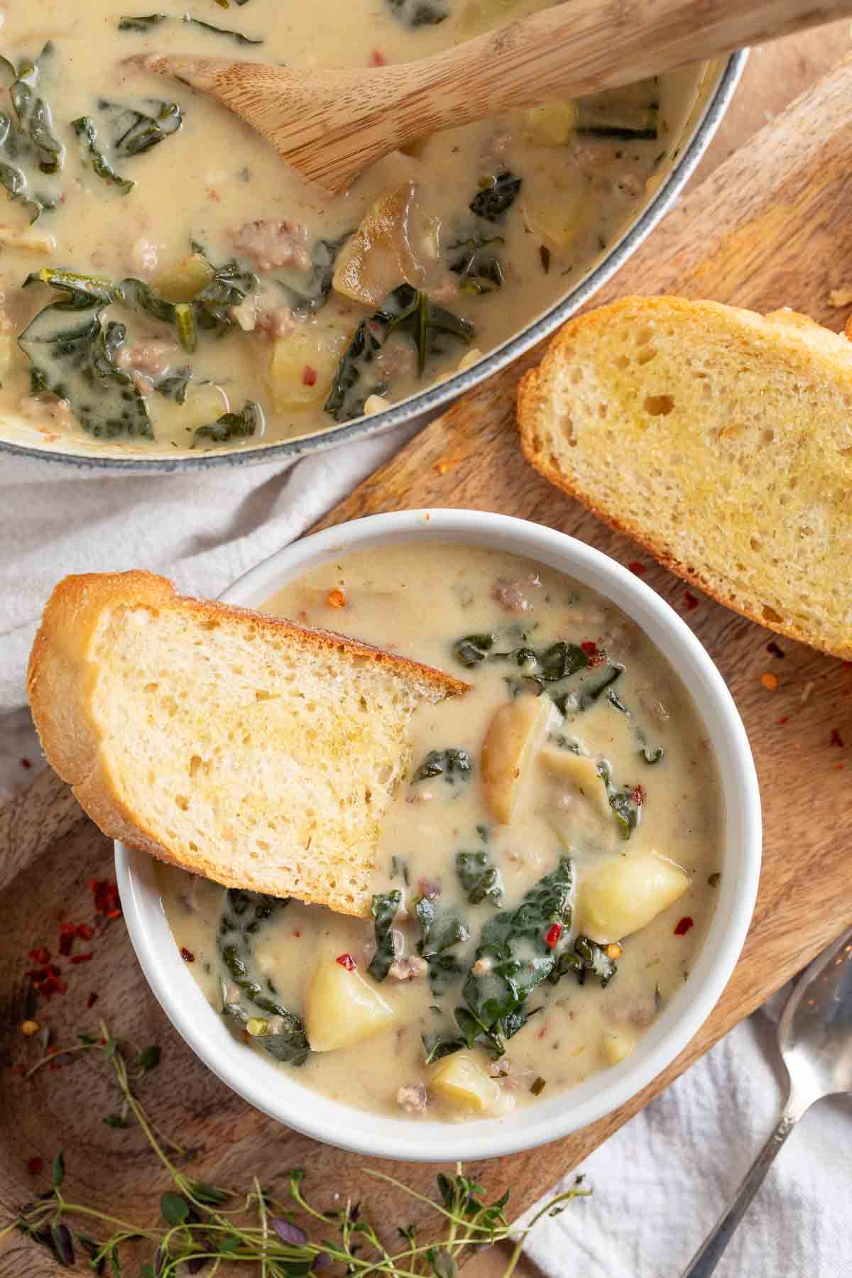 creamy italian soup in a bowl with crusty bread on top
