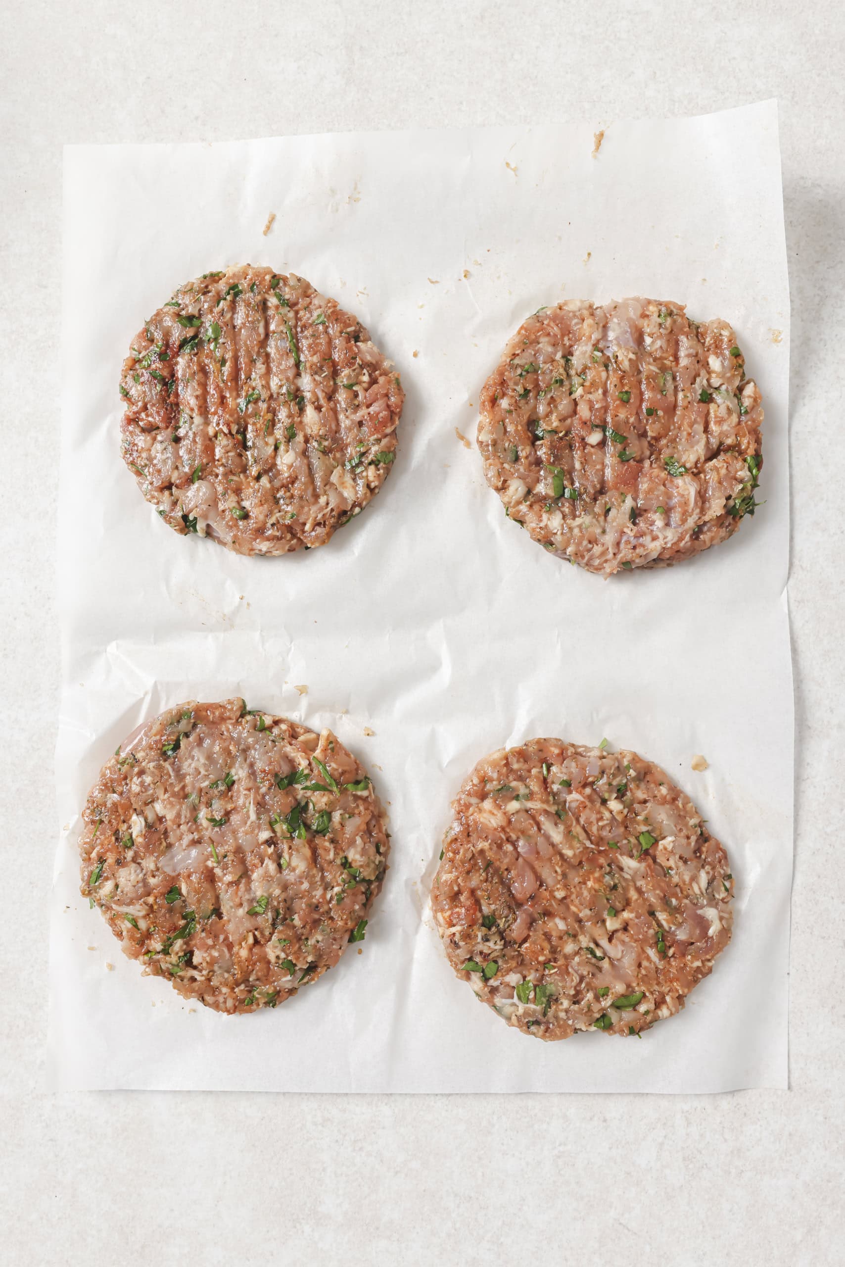 chicken burgers pattied out on parchment paper
