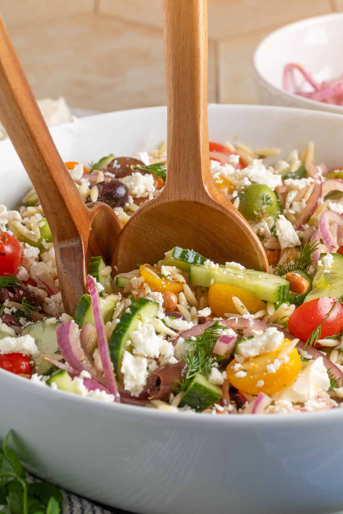 close up of orzo salad with wooden spoons