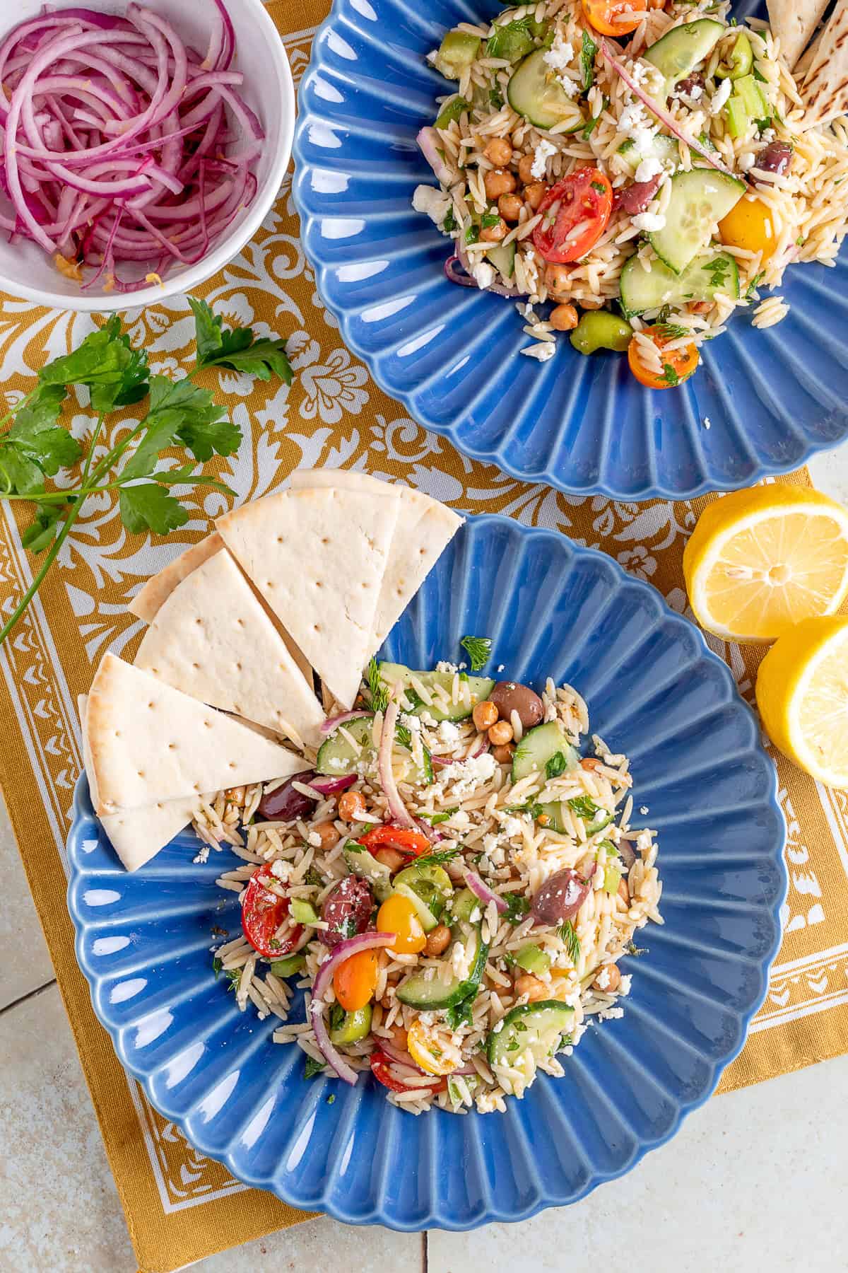 two blue plates with orzo salad and pita slices