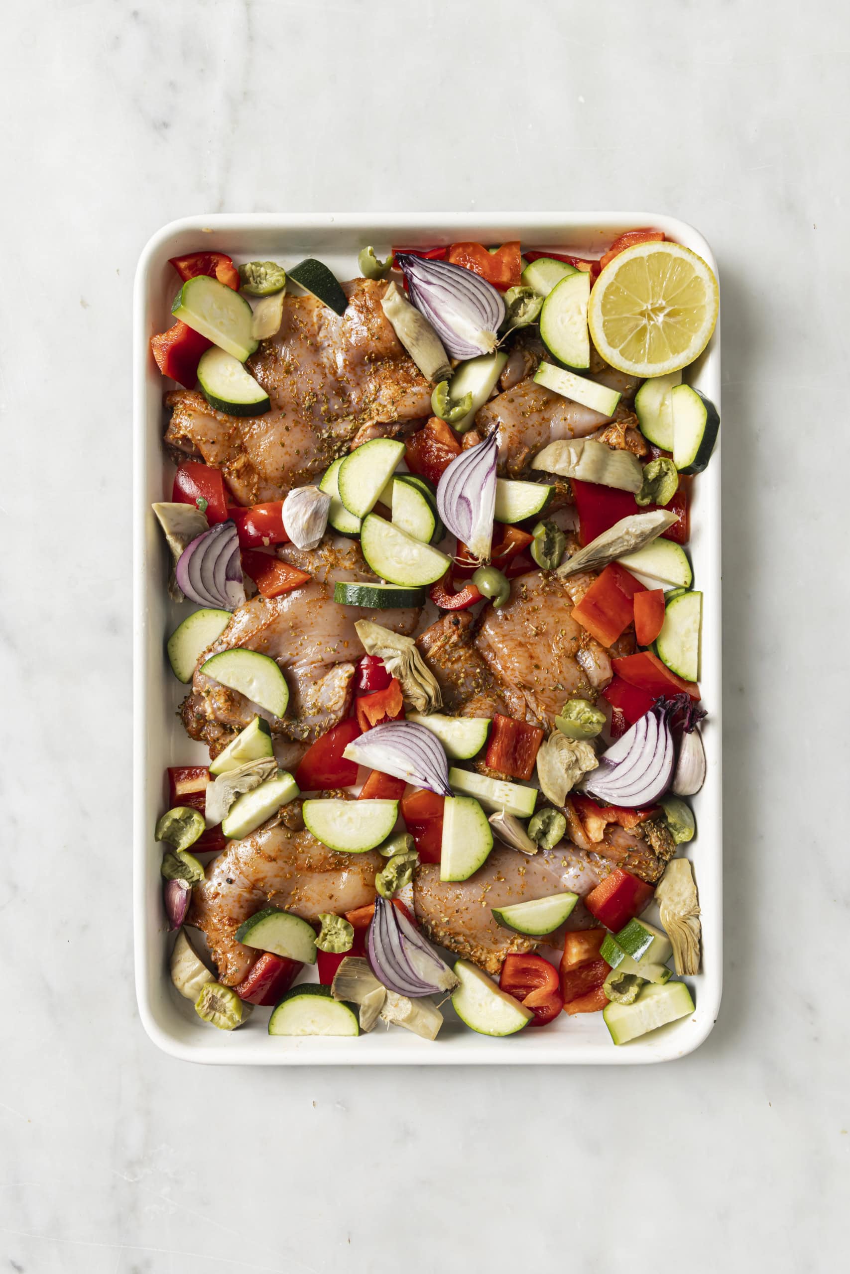 raw chicken with vegetables on sheet pan