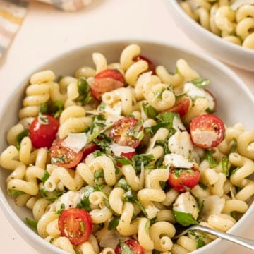Two bowls of pasta with tomatoes and herbs.