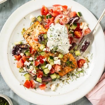 salmon with greek topping on a white plate