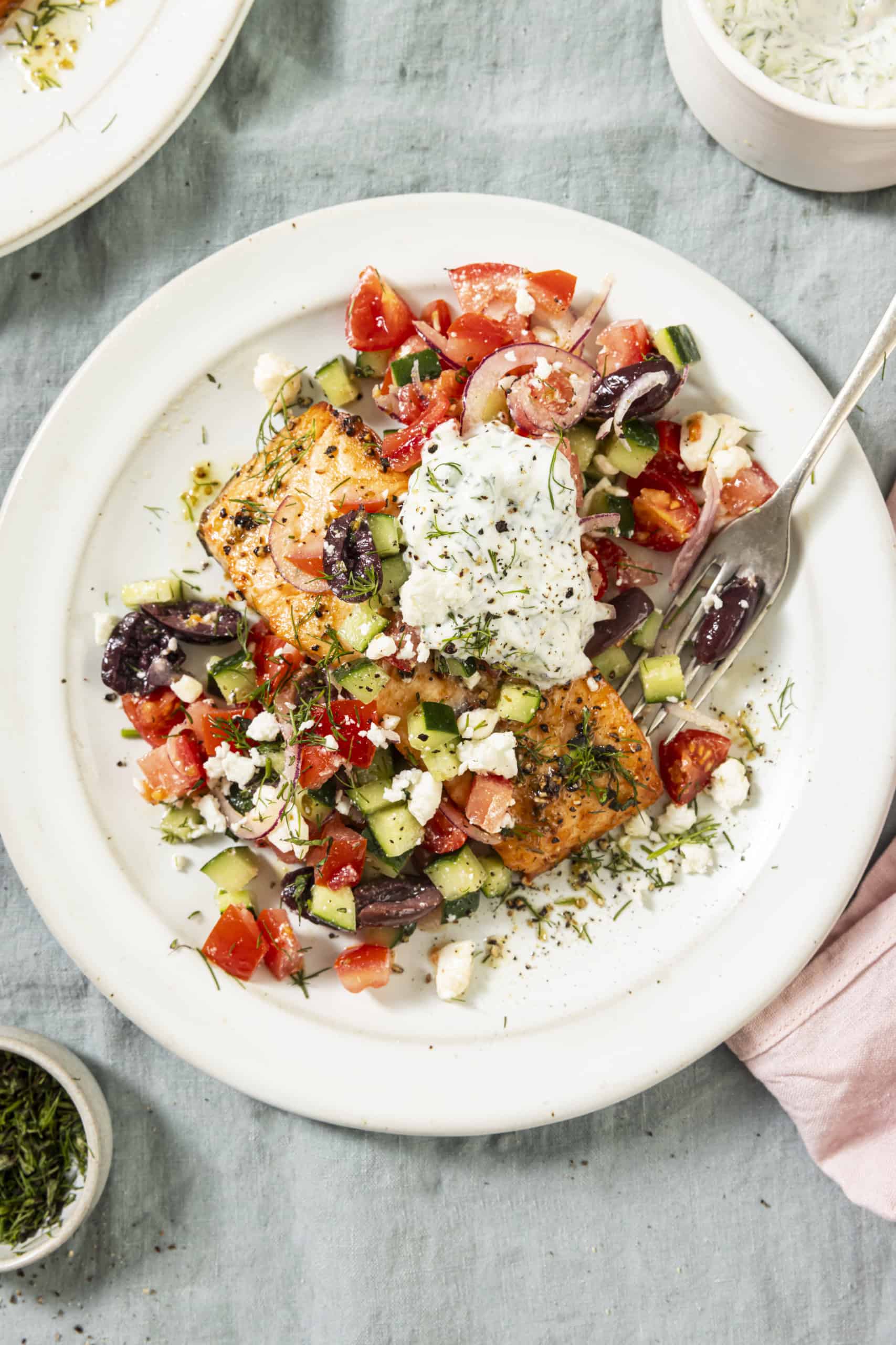 salmon with greek topping on a white plate