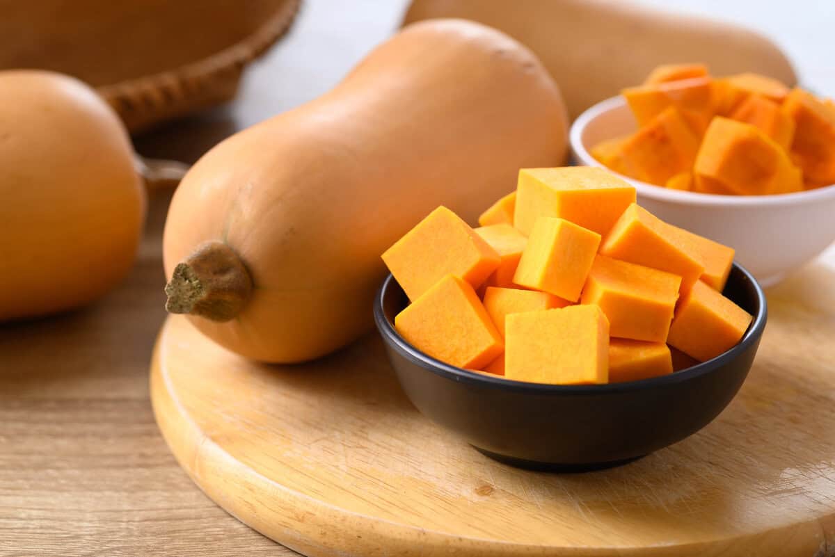 full butternut squash on wooden board with cut squash on side