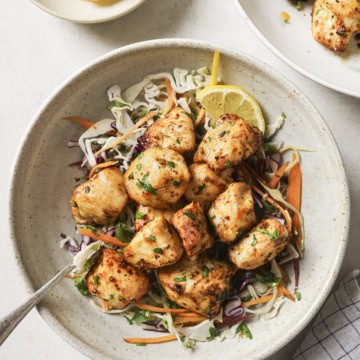 Juicy grilled chicken bites served over fresh crunchy coleslaw with lemon wedges. Perfect healthy recipe for any season