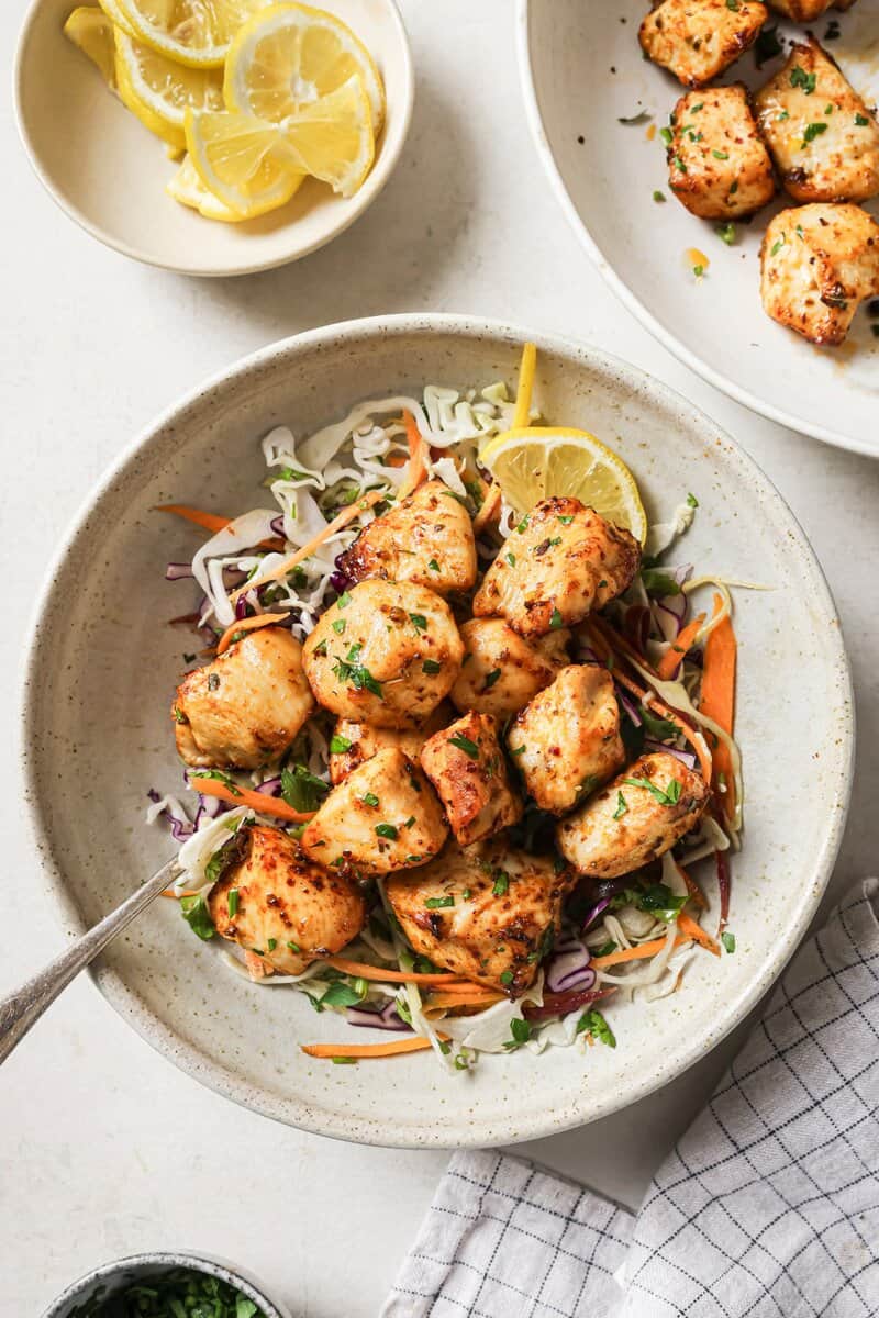 Juicy grilled chicken bites served over fresh crunchy coleslaw with lemon wedges. Perfect healthy recipe for any season