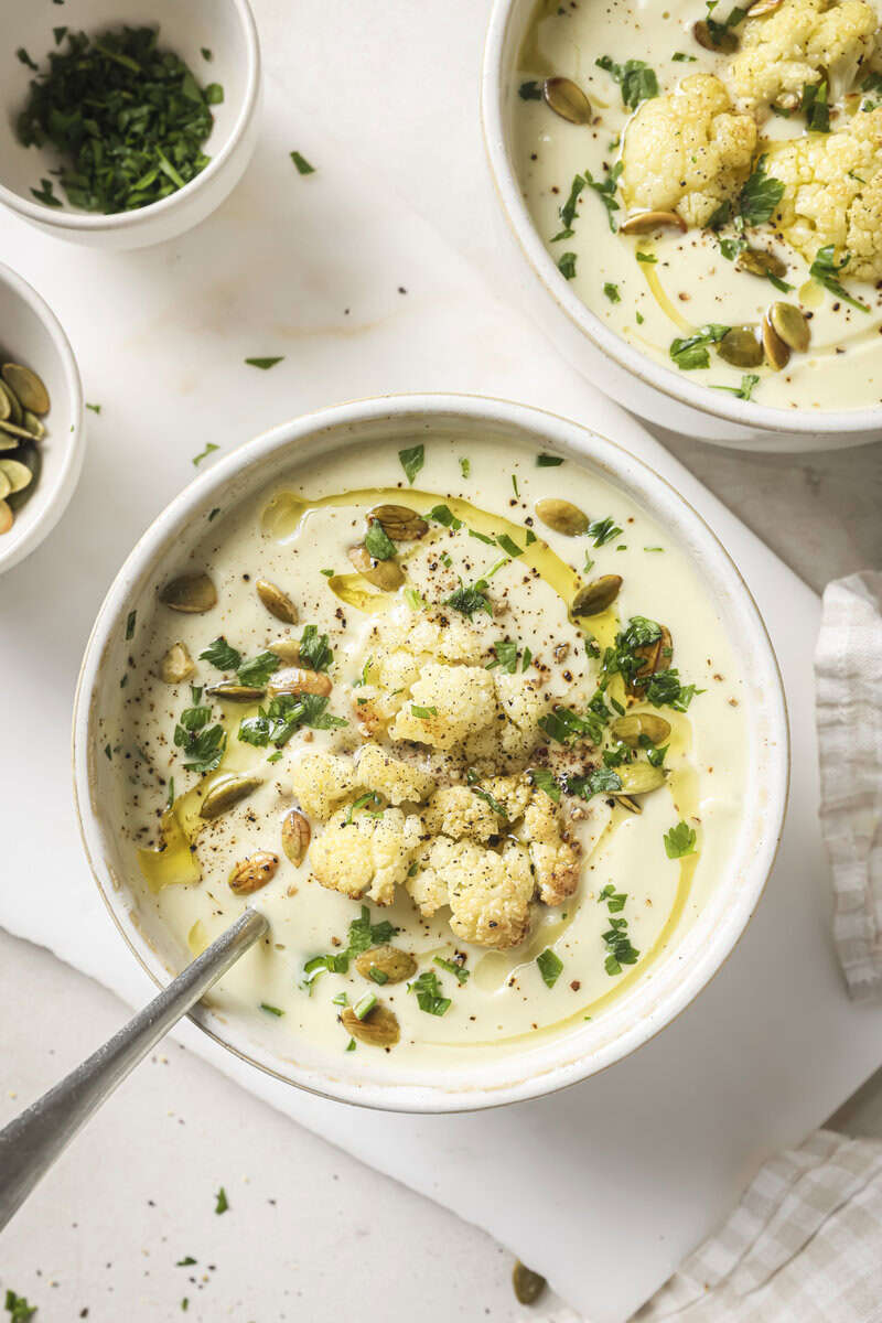 roasted cauliflower soup in a bowl with garnishes