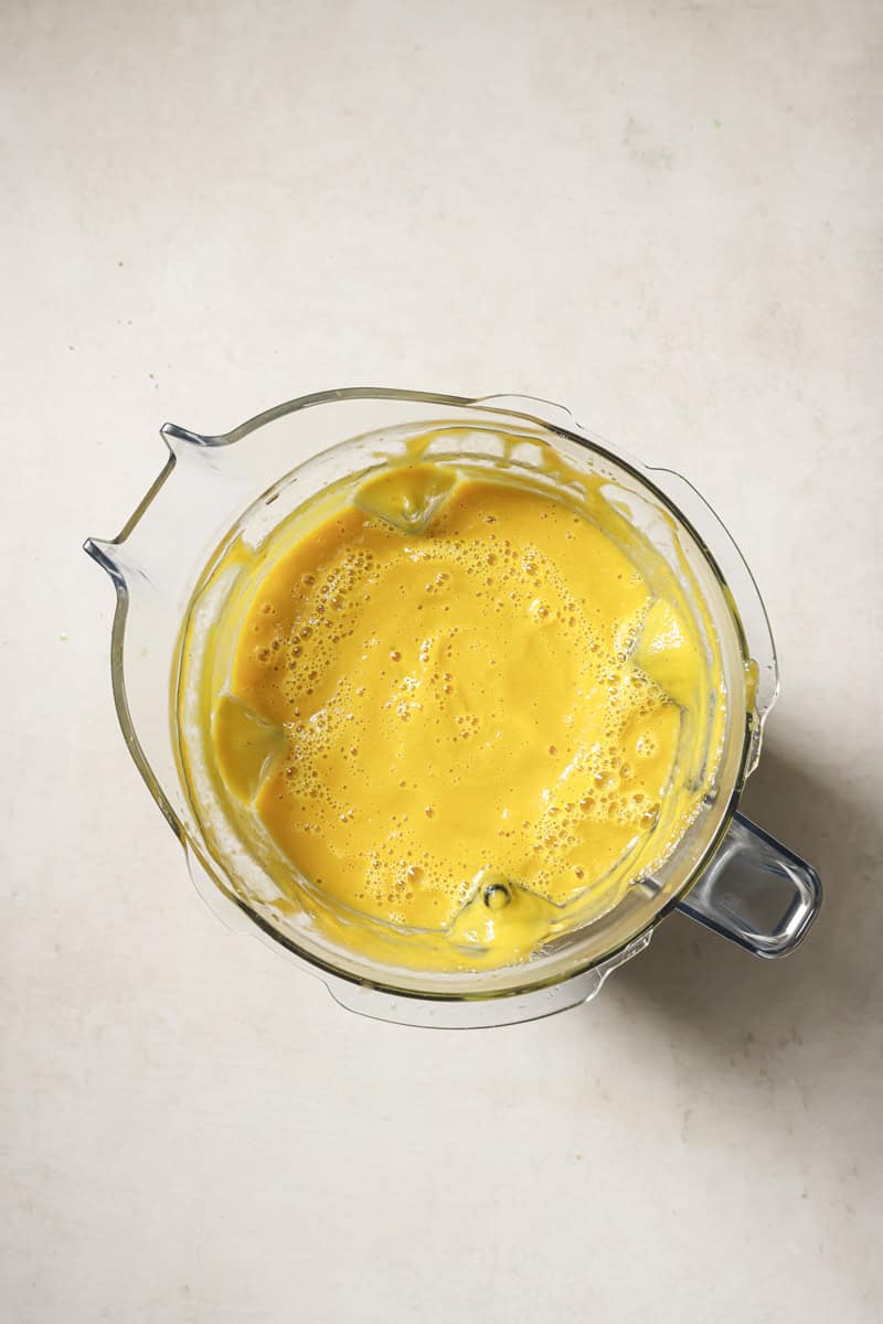 Silky smooth blended butternut soup in a glass measuring cup.