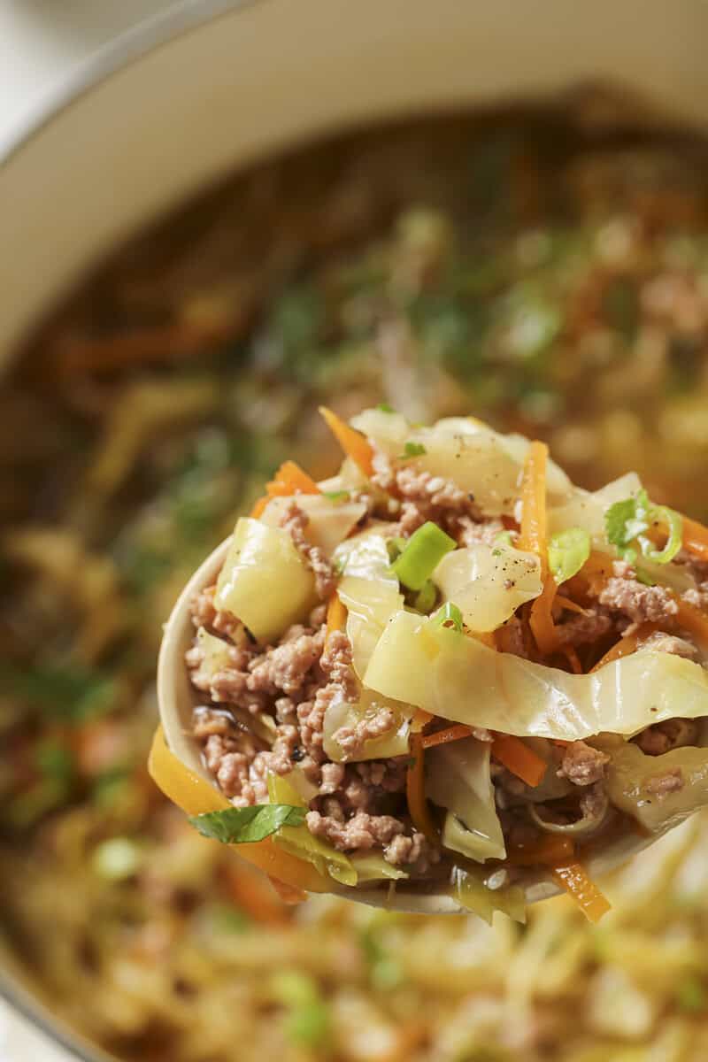egg roll soup in a dutch oven with a wooden spoon 