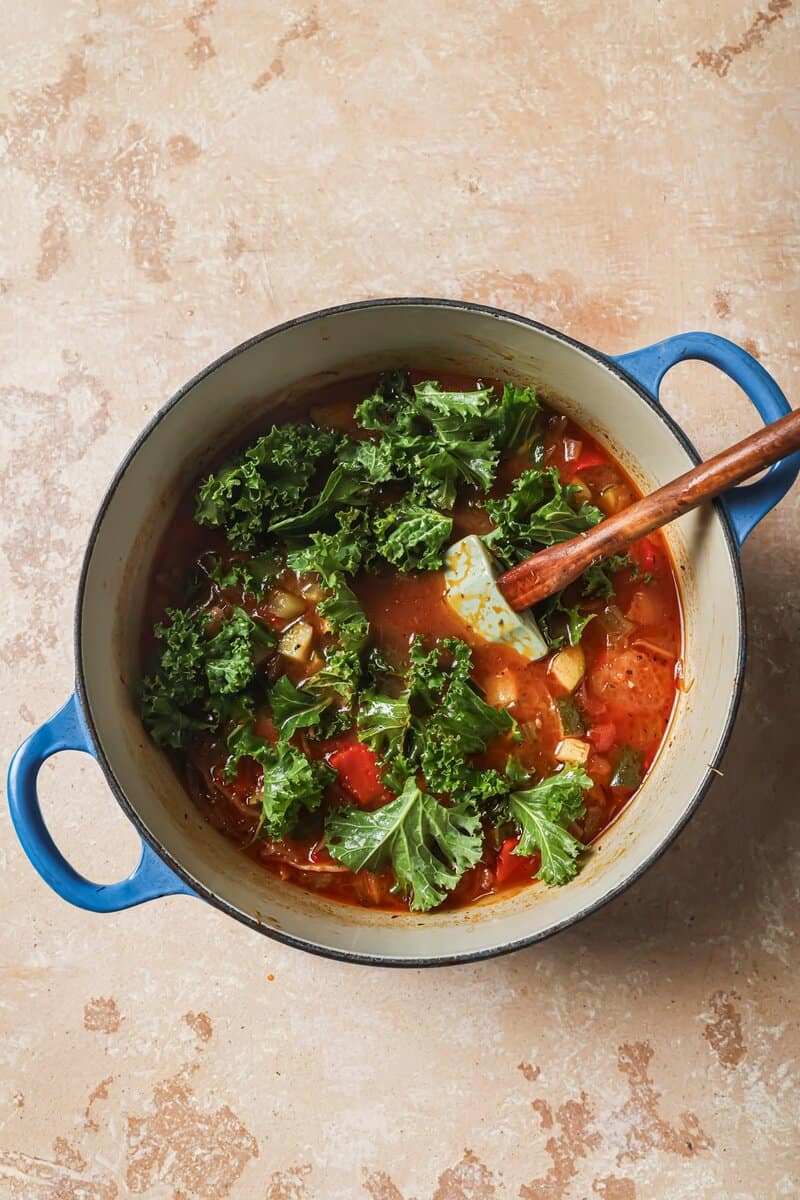 kale greens added to soup in a dutch oven