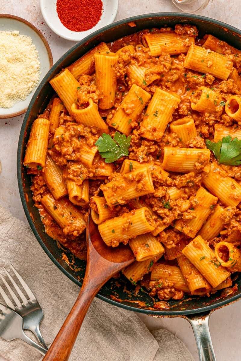creamy chorizo pasta in a skillet with a wooden spoon