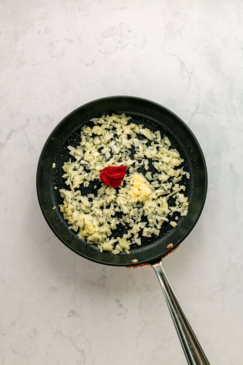 diced onions in pan with garlic and tomato paste