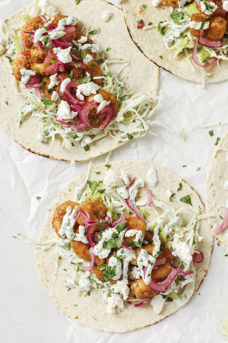 shrimp tacos with coleslaw, avocado sauce and red onions