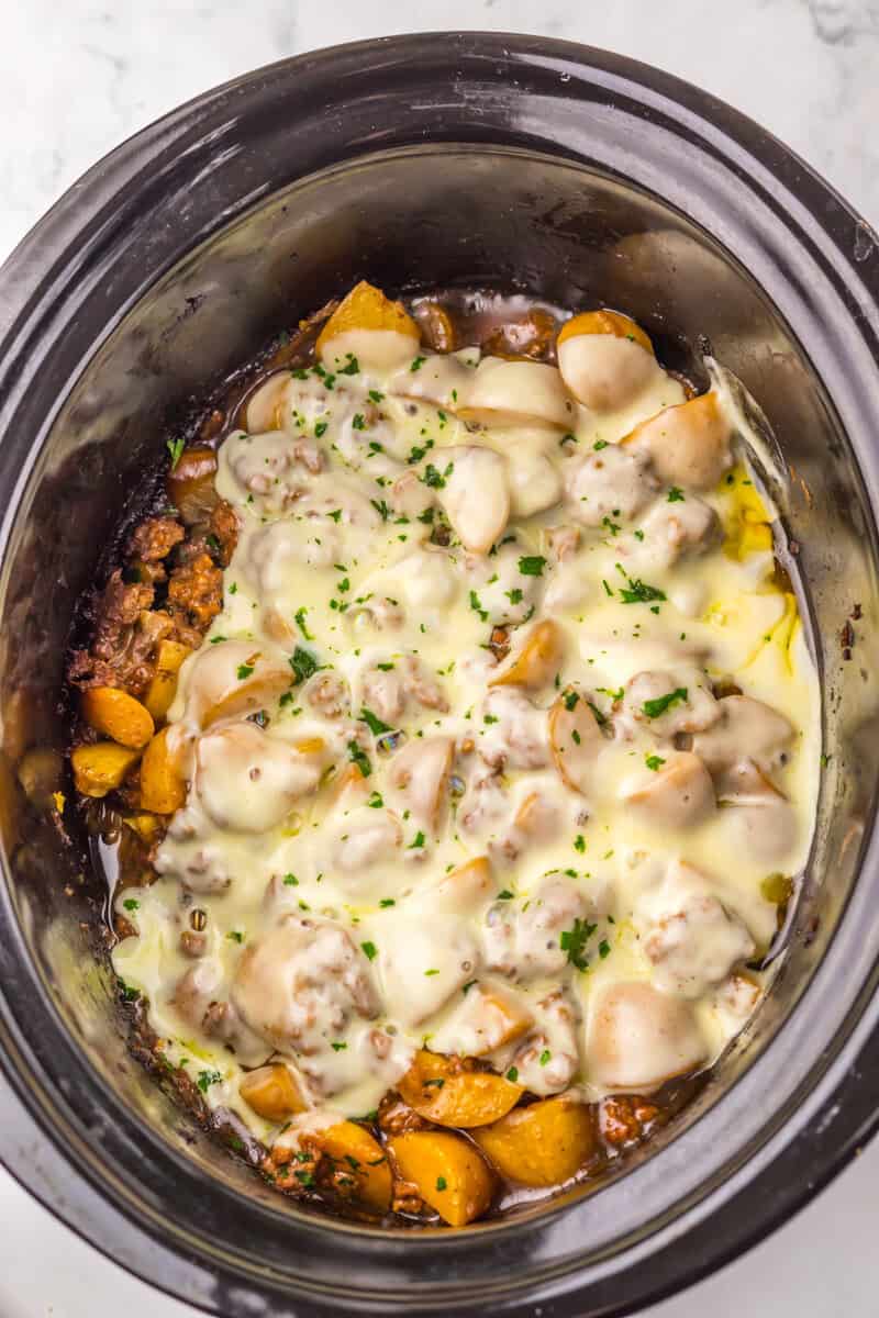cheese on top of meat and potatoes in slow cooker