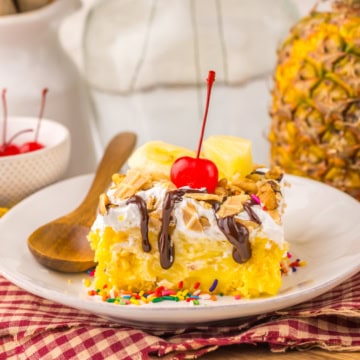 slice of banana split poke cake with cherry on top