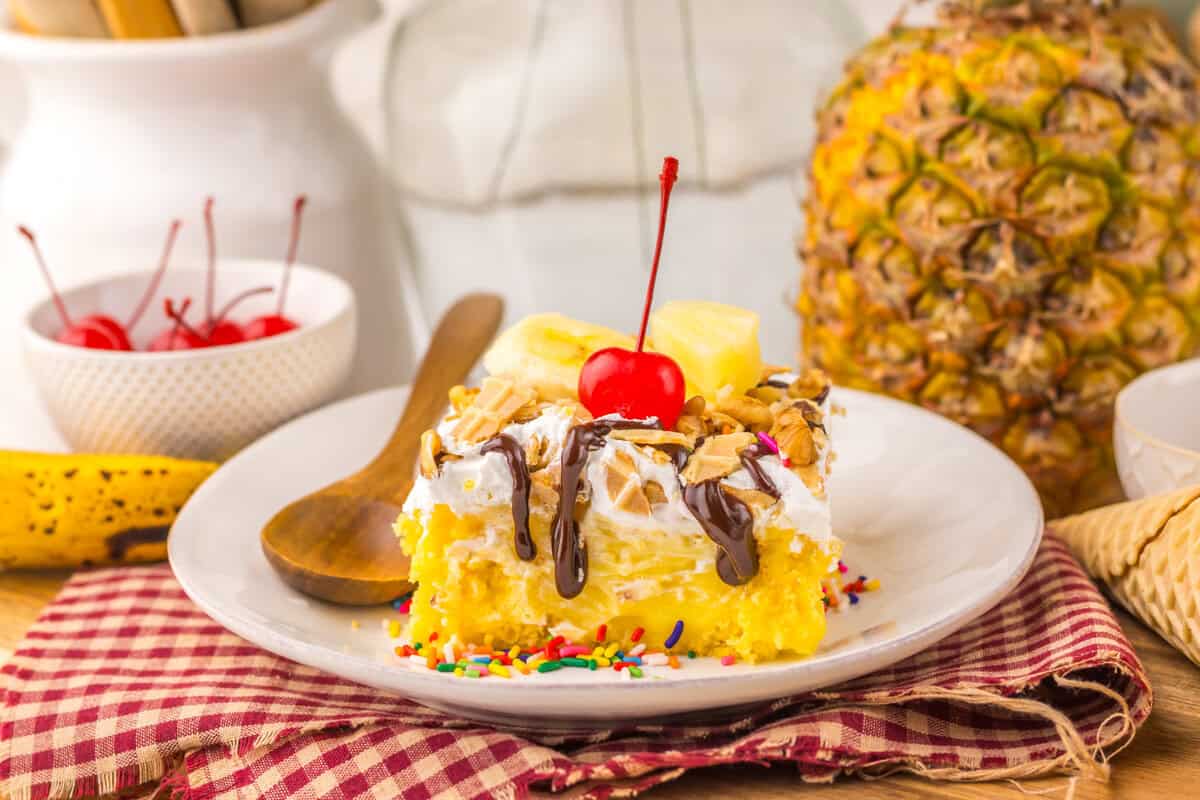 slice of banana split poke cake with cherry on top