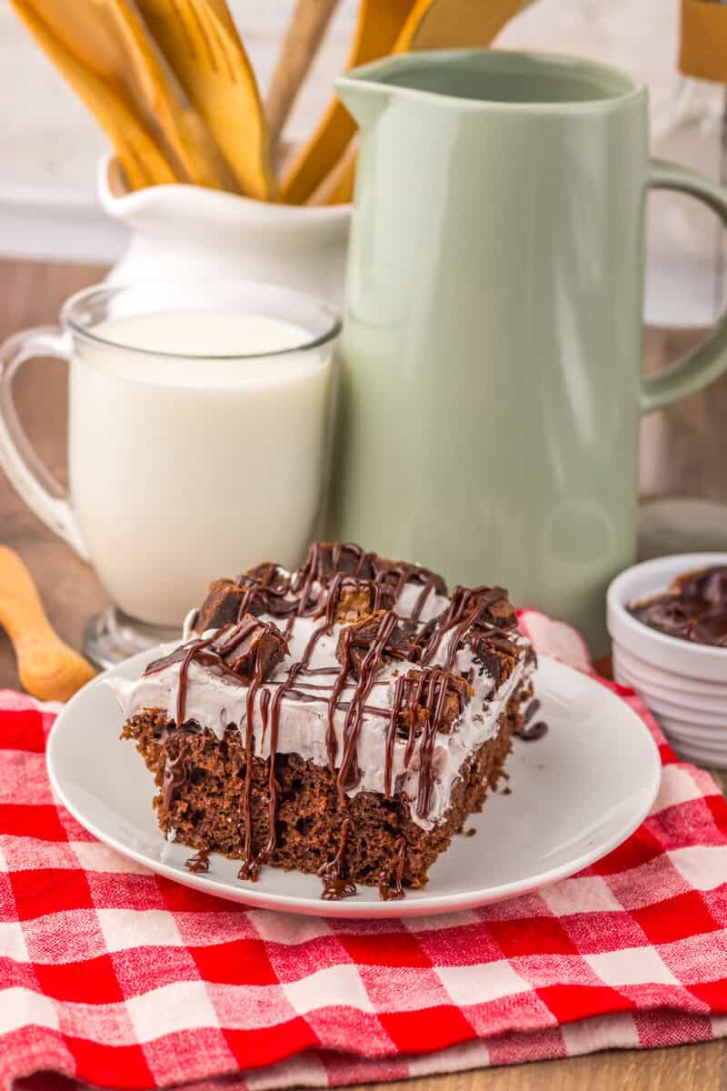 piece of chocolate poke cake on a plate with milk on side