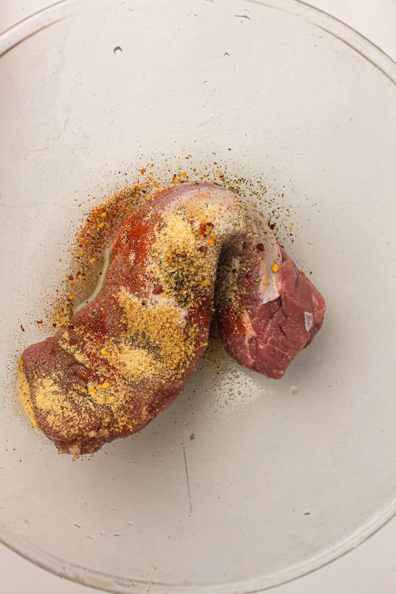 pork tenderloin with oil and spices in a bowl