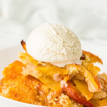 bowl full of peach cobbler with vanilla ice cream