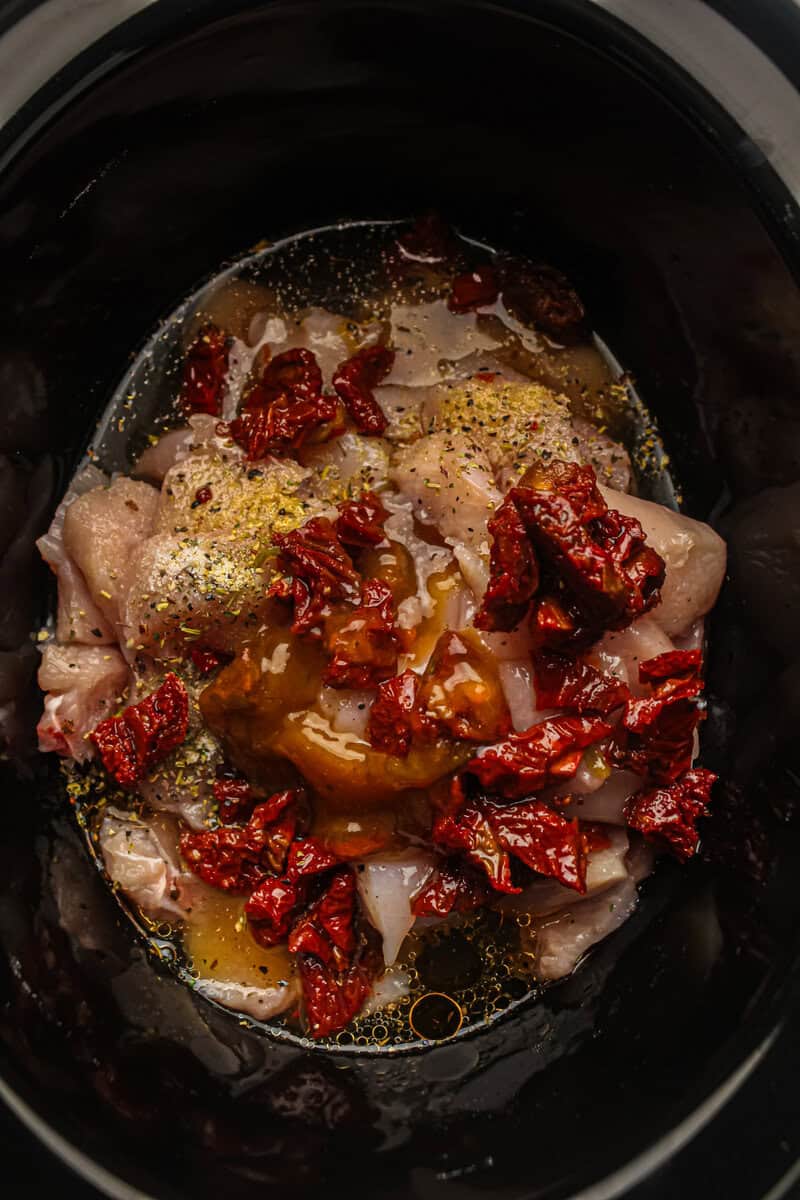 ingredients and raw chicken in slow cooker