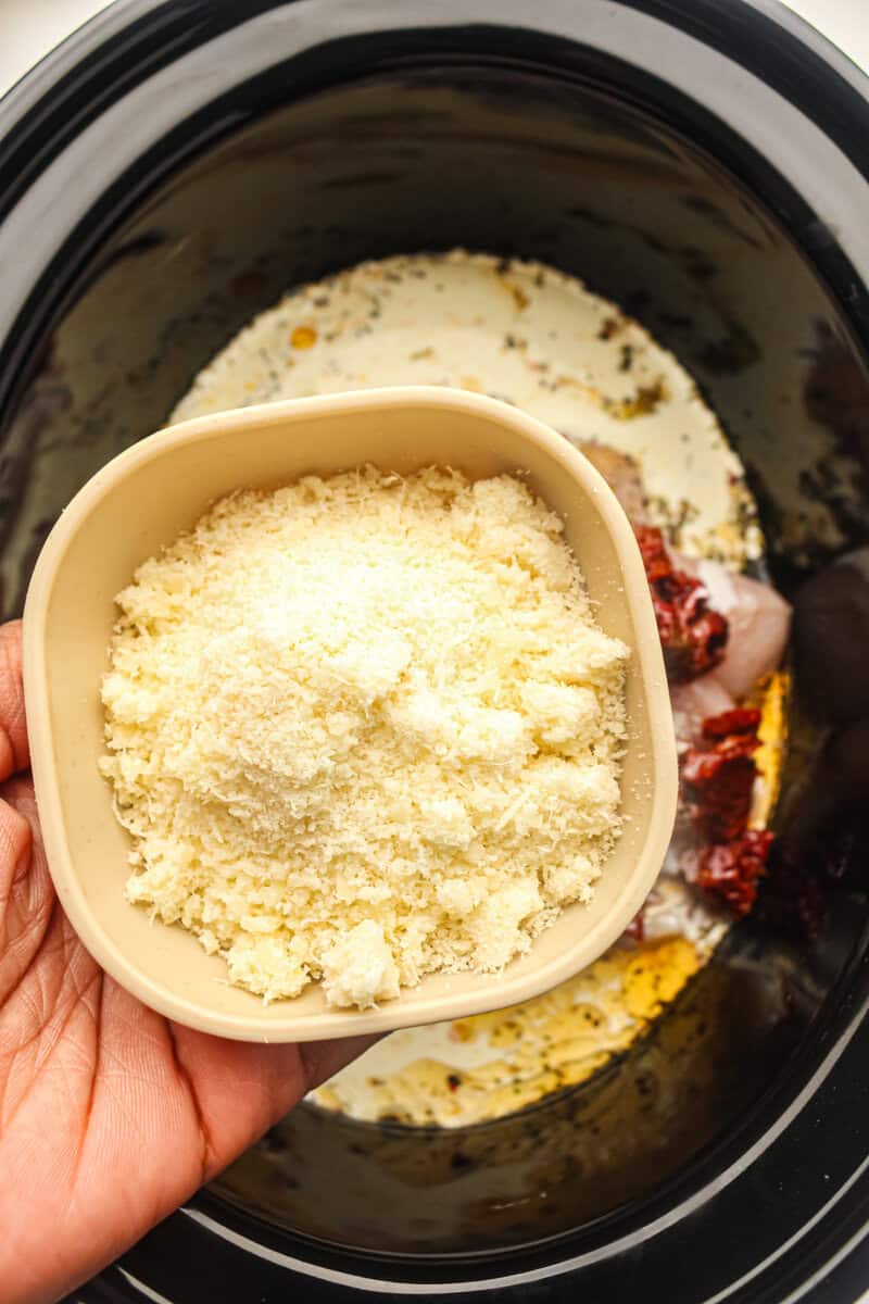 parmesan being added to the slow cooker chicken