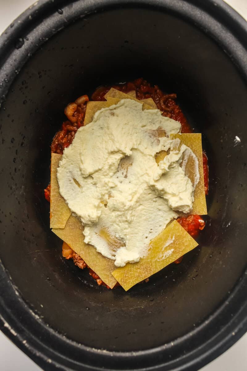 ricotta cheese layer on top of lasagna noodles in crock pot