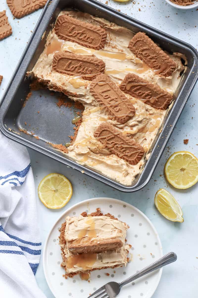 A Biscoff cheesecake with a slice removed, sitting on a white plate with a fork nearby.