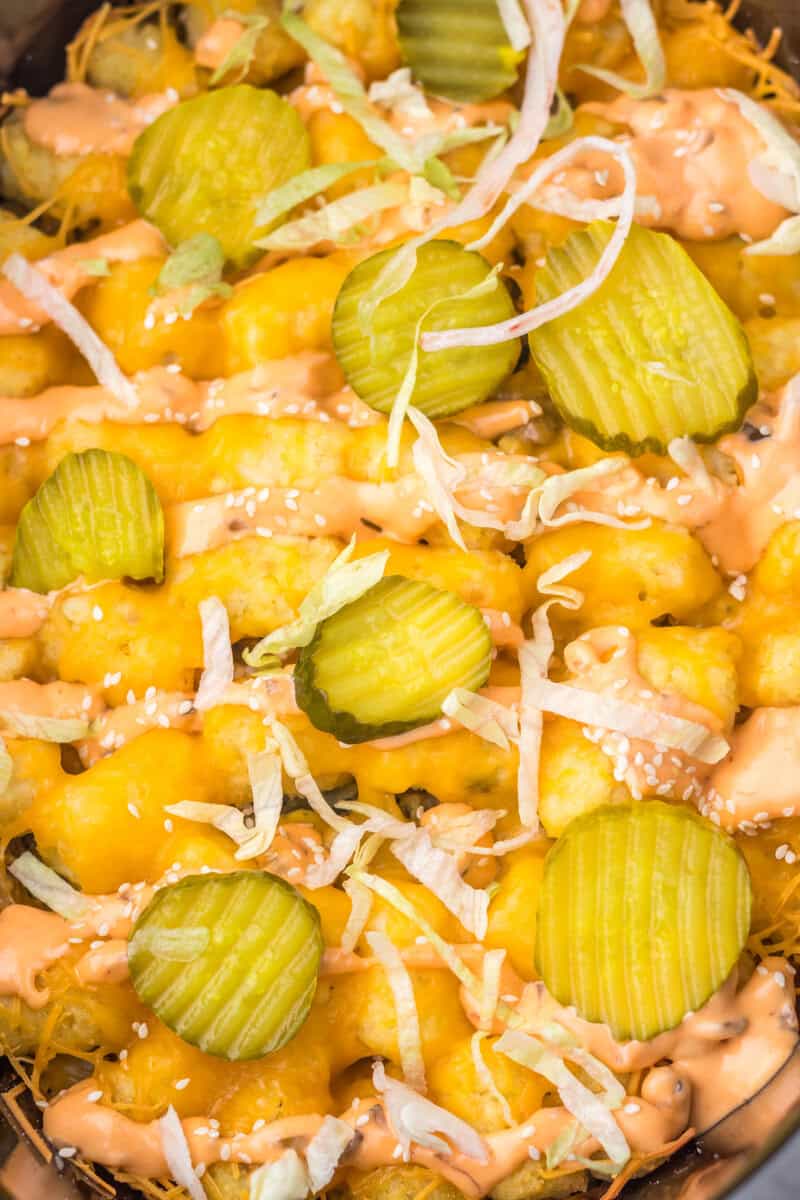 Tater tots topped with melted cheese, sliced pickles, shredded lettuce, sesame seeds, and a drizzle of orange sauce—just like your favorite Big Mac in Tater Tot Casserole form.