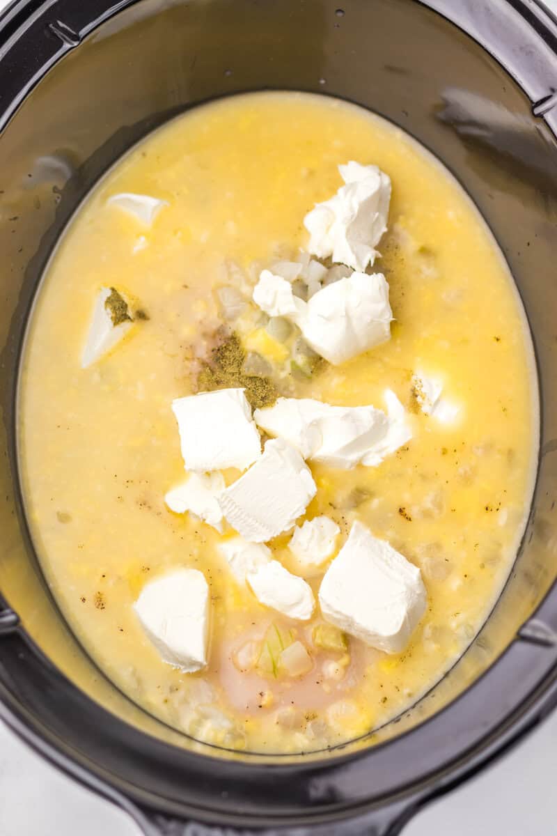 Adding all the ingredients into the slow cooker for the chicken pot pie pasta recipe.