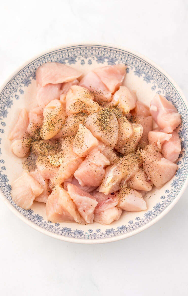 Seasoned raw chicken in a blue and white bowl.