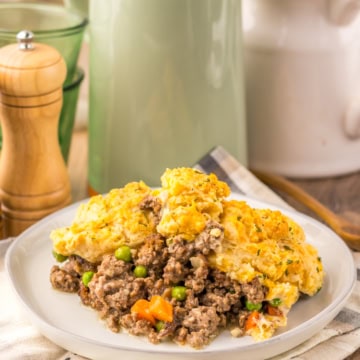 A plate of Cheddar Bay Ground Beef Cobbler on a wooden surface with a white linen underneath.