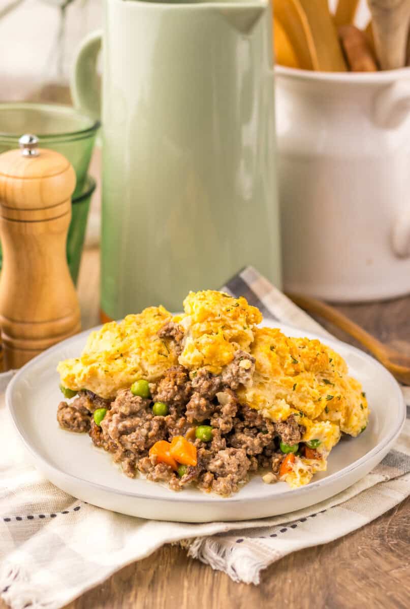 A plate of Cheddar Bay Ground Beef Cobbler on a wooden surface with a white linen underneath.