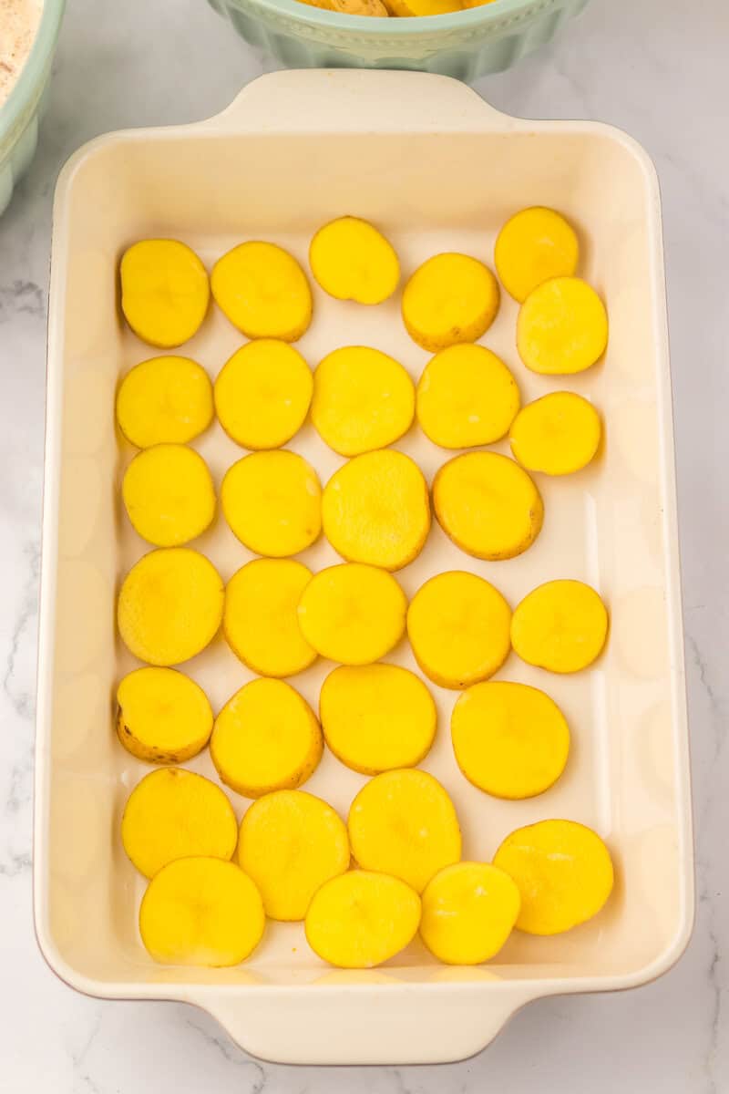 Sliced potatoes in a ceramic casserole dish.