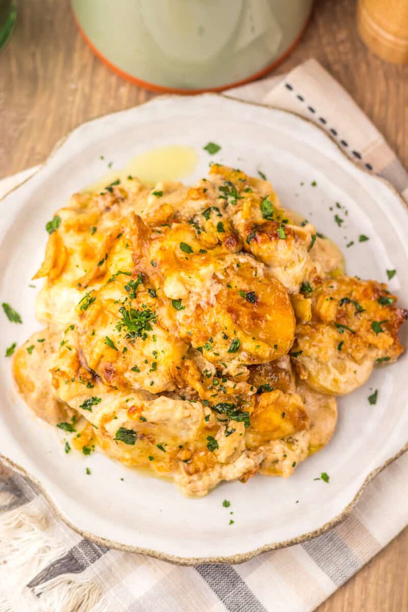 Cheesy potato casserole on a white plate on a wooden surface.
