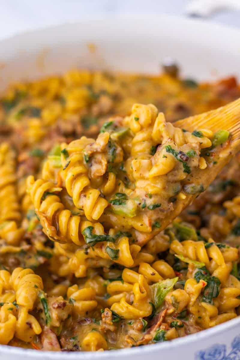 A spoon lifting a serving of Tuscan chicken pasta out of a pot.