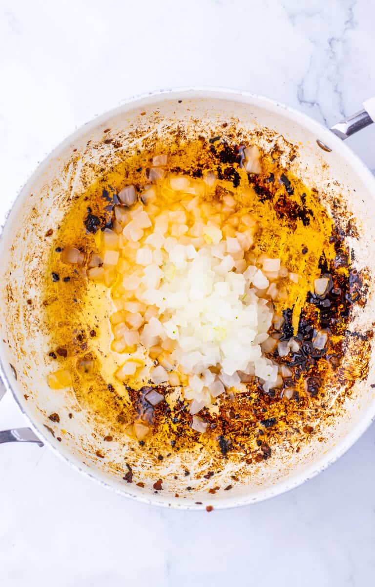 Onions cooking in a pot with grease from the sausage.