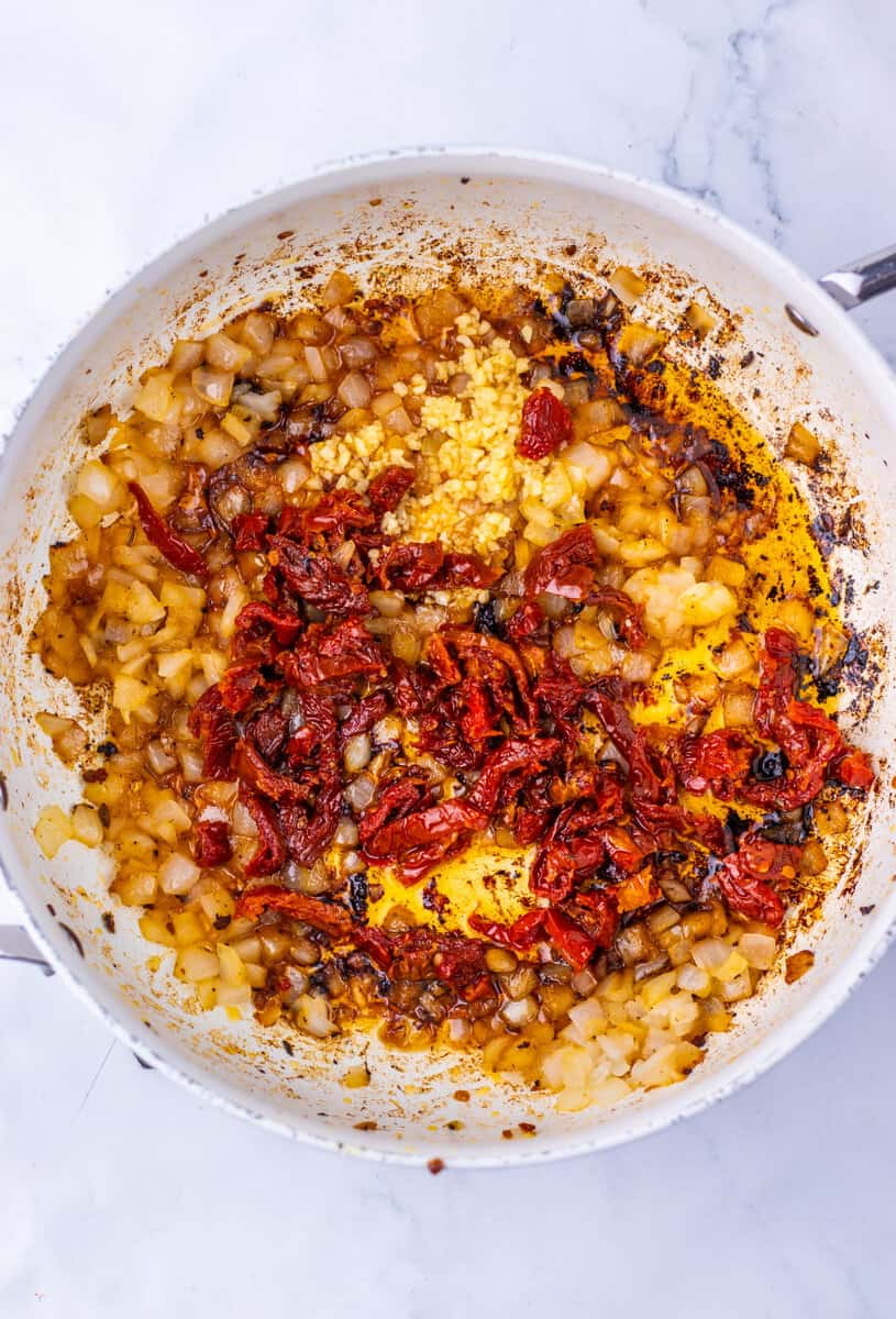 Doced onions, sundried tomatoes, and garlic in a greased Dutch oven.