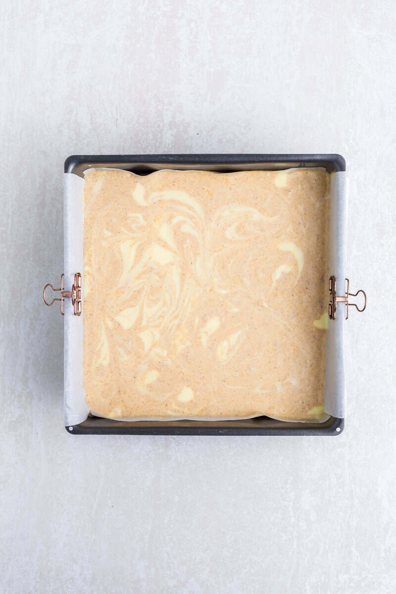 Unbaked pumpkin cheesecake bars in a metal pan.