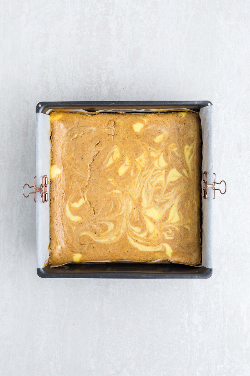 Unsliced pumpkin cheesecake bars in a metal pan.