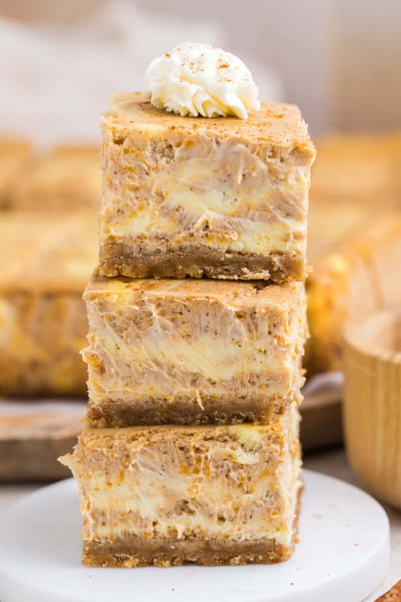 Three pumpkin bars stacked on a white plate.