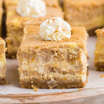 A cheesecake pumpkin bar topped with whipped cream.