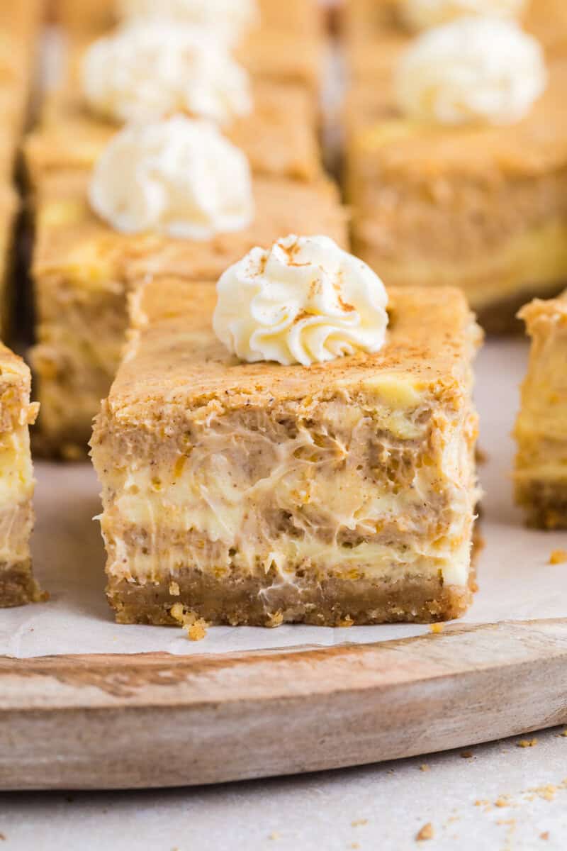 A cheesecake pumpkin bar topped with whipped cream.
