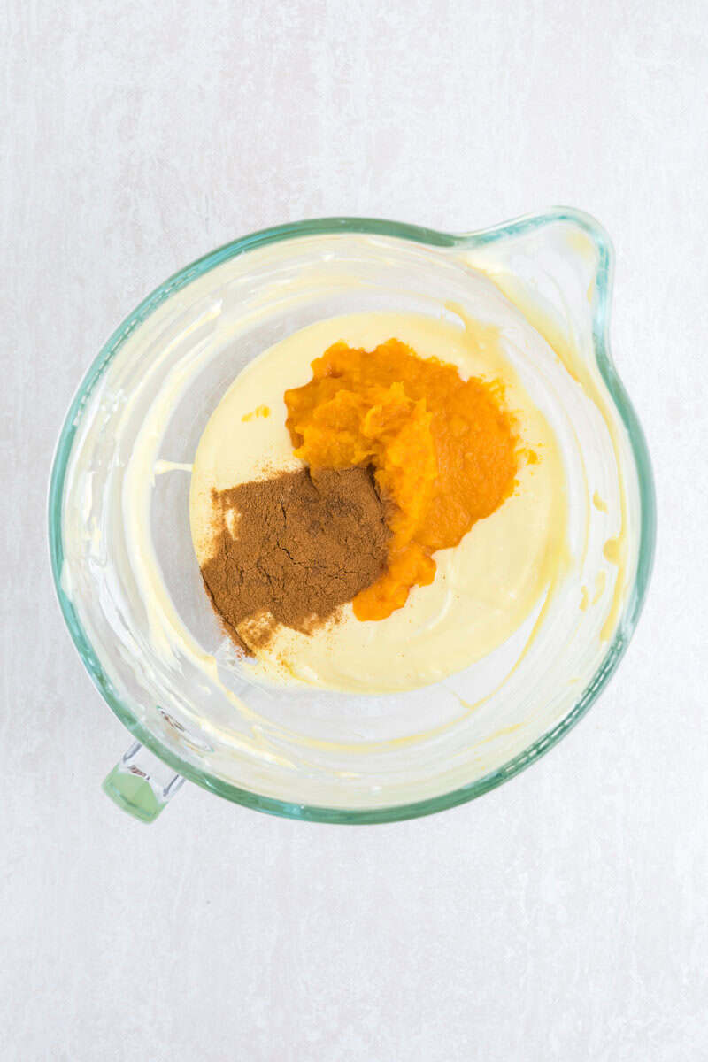Pumpkin puree, pumpkin pie spice, and cheesecake filling in a large glass measuring cup.