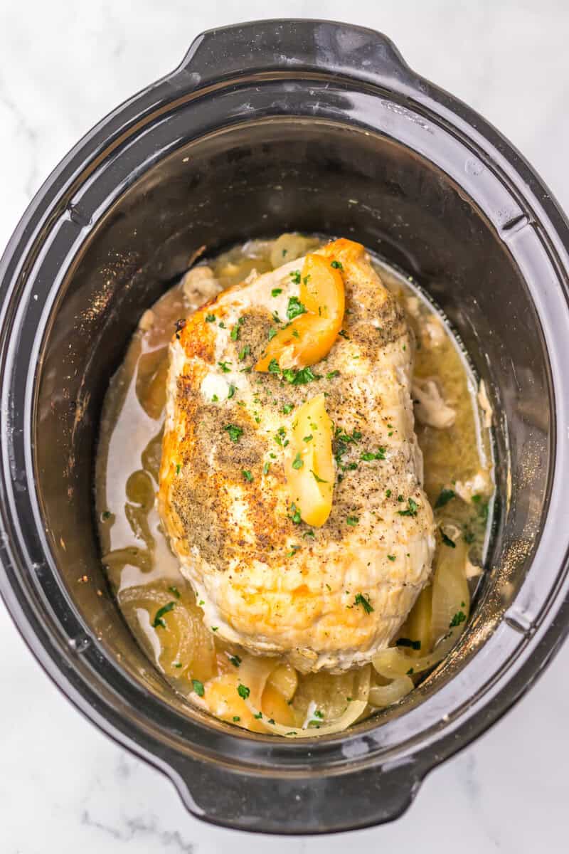 A cooker turkey breast in a black slow cooker.