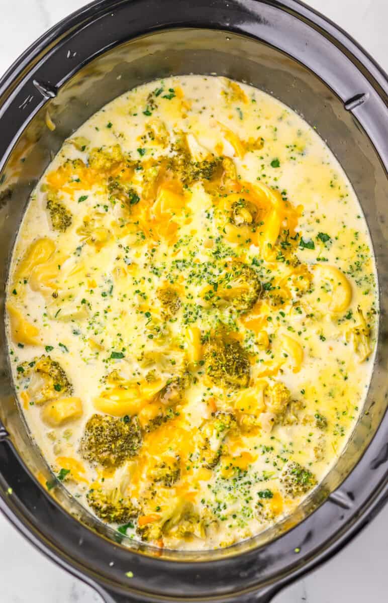 A slow cooker full of broccoli cheddar tortellini soup.