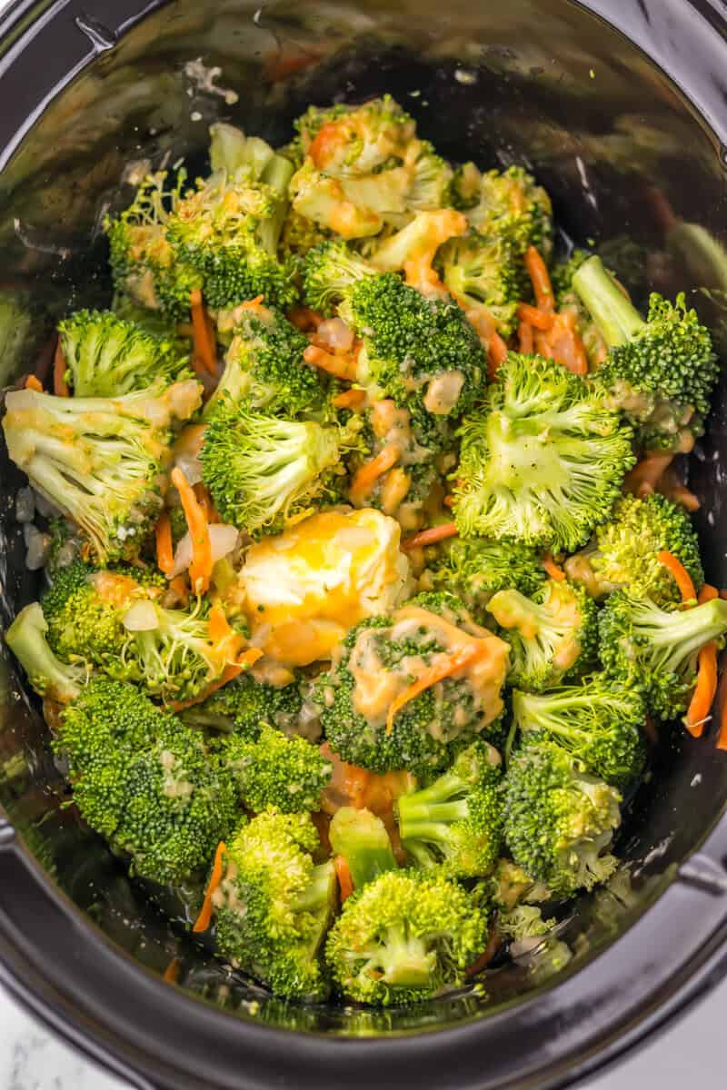 Vegetables in a slow cooker with cheese sauce and butter.