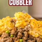 A serving of Cheddar Bay ground beef cobbler with vegetables, topped with a golden biscuit crust, is presented on a white plate.