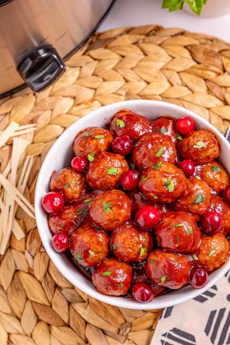 A white bowl of meatballs with toothpicks nearby.