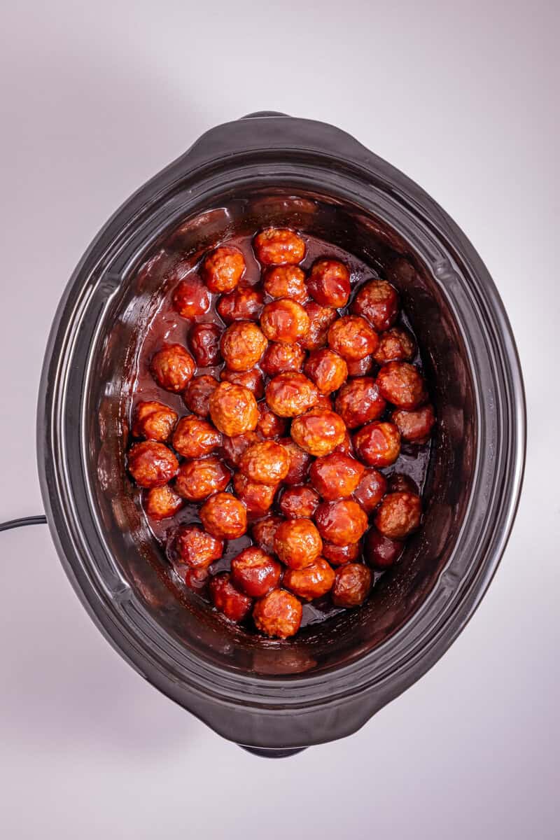 A slow cooker with meatballs and sauce.
